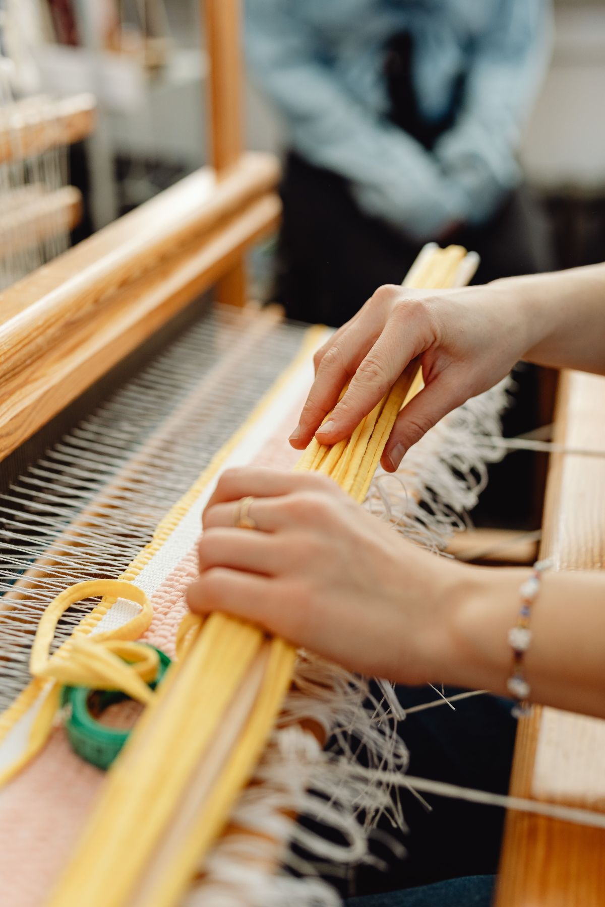 An artisan's hands working threads on a wooden loom
