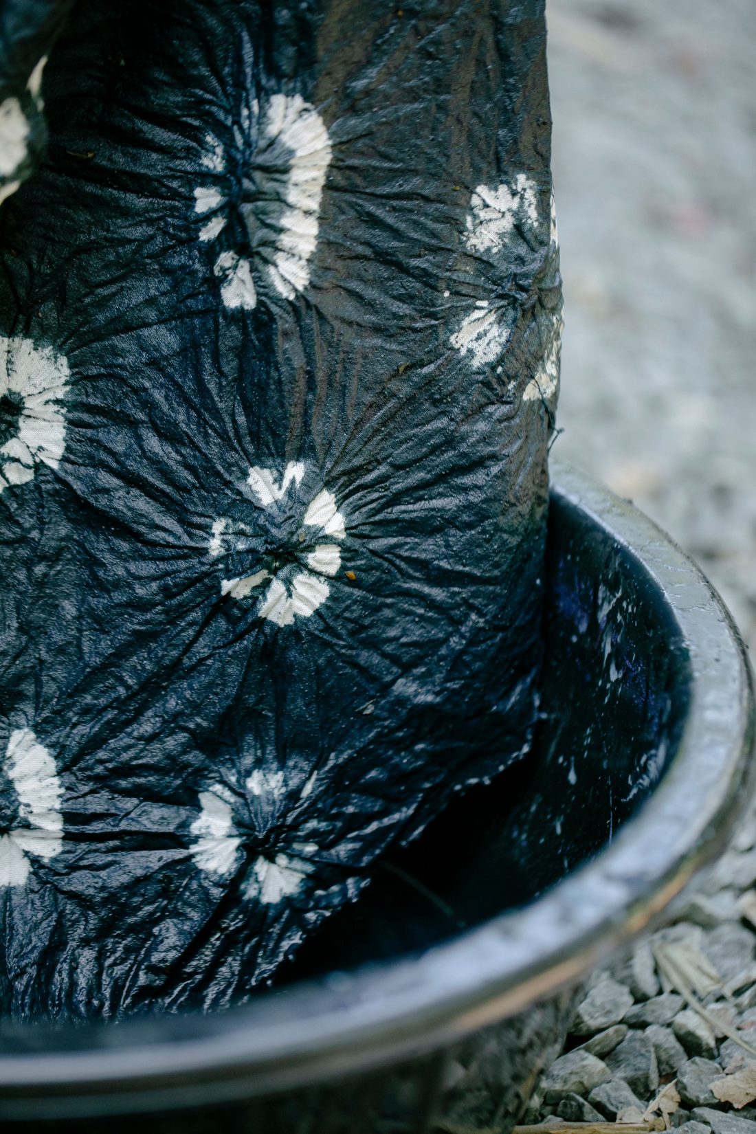 Bundled indigo shibori-dyed cloth resting in a dye vat